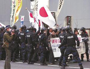 警察官に囲まれて、京都朝鮮第一初級学校までヘイトスピーチをしながら歩くグループの写真