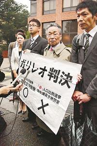 名古屋高裁前で、「ガリレオ判決」と書いた紙を掲げる原告の弁護士らの写真