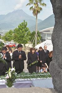 慰霊碑の前で祈る遺族らの写真