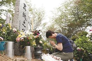 墜落現場の慰霊碑の前で手を合わせる女性