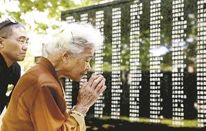 沖縄平和祈念公園にある戦没者の名前を刻んだ平和の礎に手を合わせる人の写真