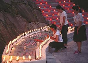 日本航空のジャンボ機墜落事故の追悼式でロウソクに点火して祈りをささげている写真