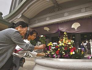 東京都慰霊堂の前に花を手向ける女性の写真