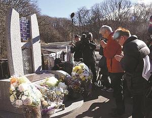 「祈りの碑」に献花する、犠牲者の遺族や友人の写真