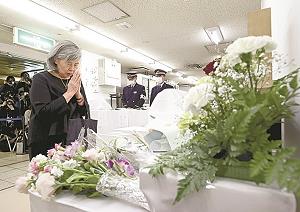 霞ケ関駅の献花台に手を合わせる女性の写真