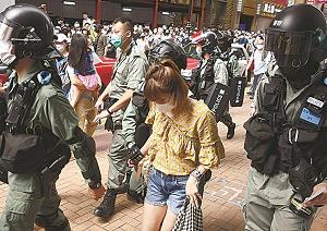 警察官に連行されるデモ参加者の女性の写真